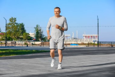 Kulaklıklı, dışarıda koşan olgun bir adam.