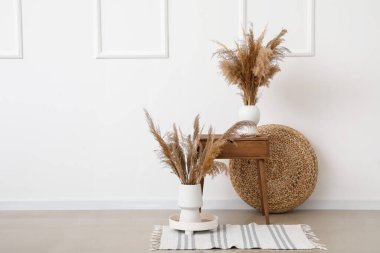 Masa ve kuru sazlıkların olduğu odanın içi aydınlık duvarın yanında