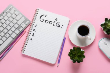 Liste yapmak için boş bir defter ve renkli fonda bir fincan kahve olan bilgisayar klavyesi. Yeni yıl hedefleri