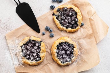 Açık arkaplanda lezzetli yaban mersini galetleriyle parşömen.