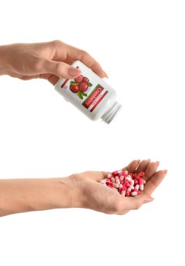 Beyaz arka planda kırmızı böğürtlen hapları ve şişe taşıyan kadın eller.