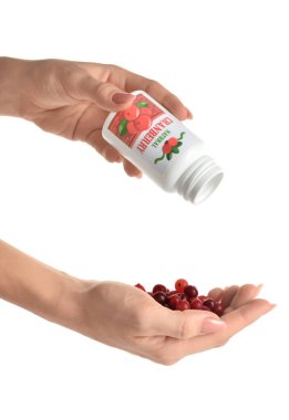 Şişeli kadın eller ve beyaz arka planda kızılcık yığını.