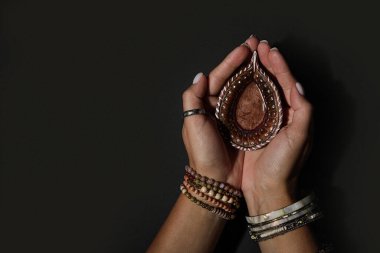 Karanlık arka planda Diwali için diya lambalı kadın eller