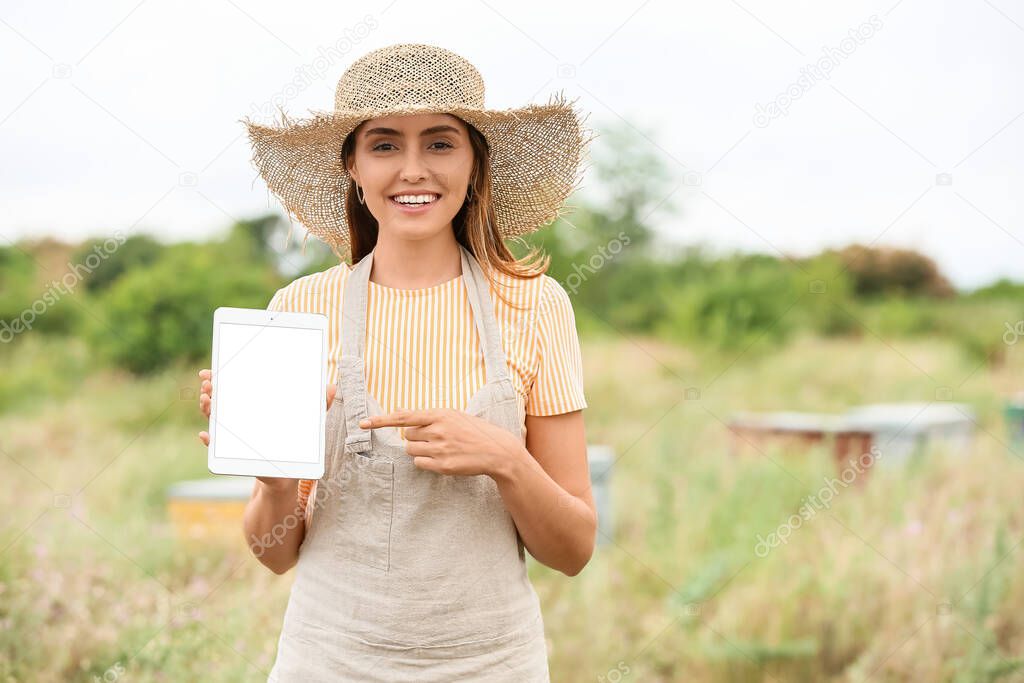 Female beekeeper with tablet computer at apiary