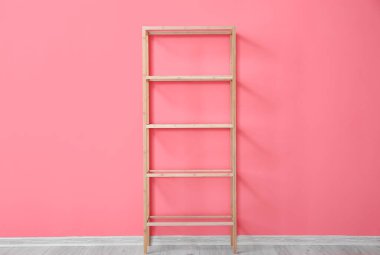 Pembe duvarın yanında şık ahşap raf ünitesi