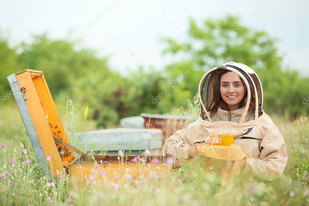 Female beekeeper with honey at apiary