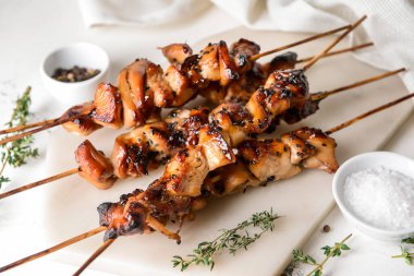 Hafif arka planda ızgara tavuk şişleri olan bir tahta.