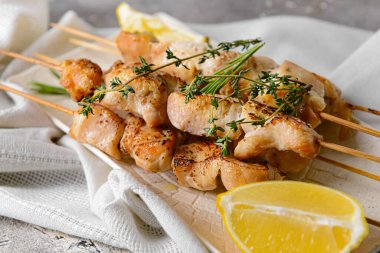 Arka planda ızgara tavuk şişleri olan tepsi.