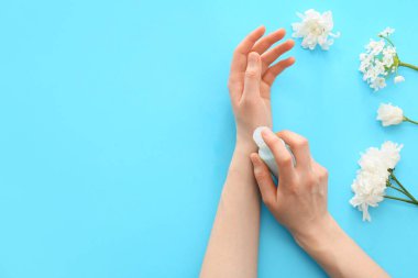 Renkli arka planda kozmetik ürünü şişesi olan kadın elleri