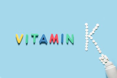 Kelime VITAMIN ve K harfi renk arkaplanındaki haplardan yapılmış.