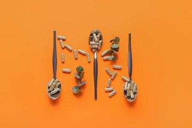 Renkli arka planda K vitamini haplı kaşıklar