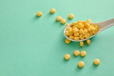 Renkli arka planda A vitamini haplı kaşık, yakın plan