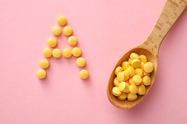 A harfi pembe arka planda kaşıklı haplardan yapılmıştır.