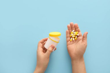 Renkli arka planda kapsülleri olan kadın elleri