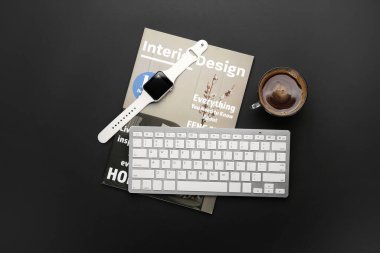 Koyu arkaplanda kahve, klavye ve dergi kompozisyonu