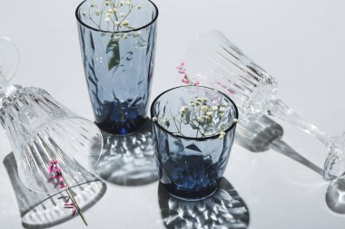 Gri arkaplanda güzel boş bardaklar ve çiçekler, yakın plan.