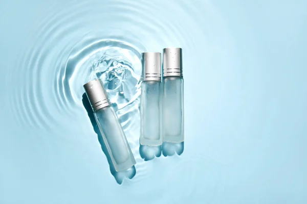 Flaschen Mit Kosmetikprodukten Wasser Auf Blauem Hintergrund — Stockfoto