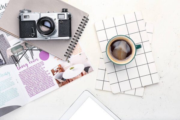 Composition with cup of coffee, photo camera and notebook on light background