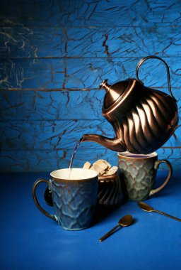 Renkli arka planda fincana sıcak çay dökmek