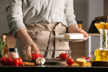 Mutfaktaki yemek masasında peynirli ve domatesli bir kadın.