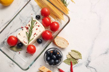 Açık arkaplanda beyaz peynirli, zeytinli ve domatesli fırın tabağı.