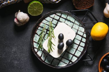 Koyu arkaplanda beyaz peynir ve zeytin tabağı.