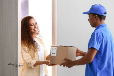 Afro-Amerikalı kadın teslimat şirketinden paket alıyor.