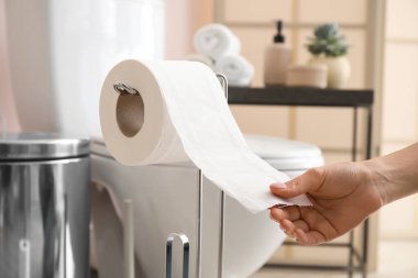 Modern banyoda tuvalet kağıdını yırtan kadın.