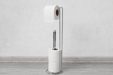 Işık duvarının yanında tuvalet kağıdı yuvarlanan modern tutucu.