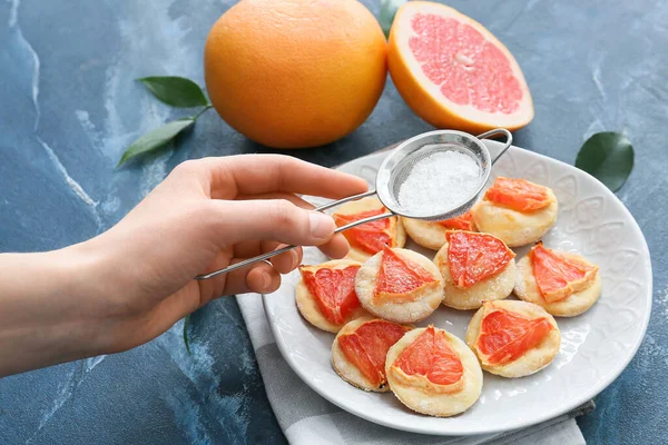 Woman Sprinkling Tasty Grapefruit Cookies Sugar Powder Color Background — Stock Photo, Image