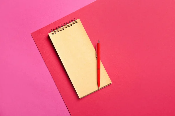 彩色背景上的空白笔记本和红色钢笔 — 图库照片