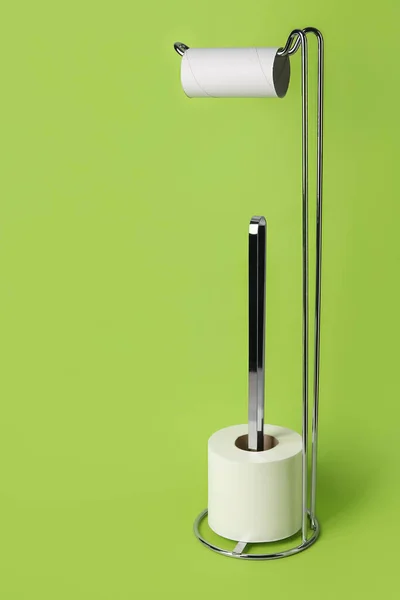 Holder with cardboard tube and toilet paper roll on green background