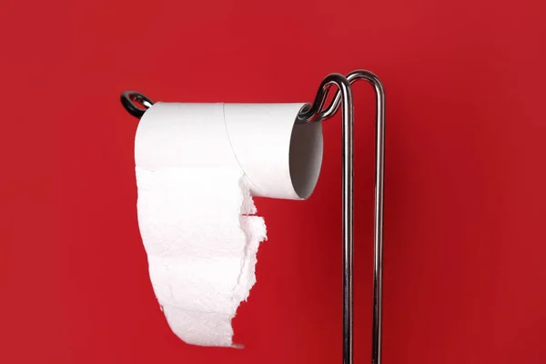 Holder with cardboard tube for toilet paper on red background, closeup