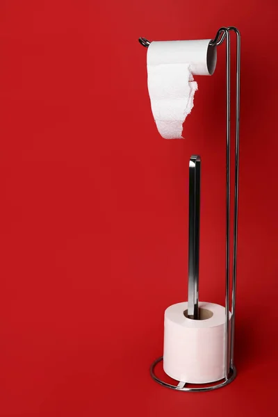 Holder with cardboard tube and toilet paper roll on red background