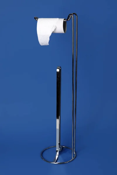Modern holder with cardboard tube for toilet paper on color background
