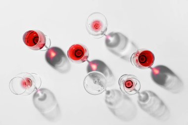 Açık arkaplanda kırmızı şarap artığı olan bardakların şık kompozisyonu