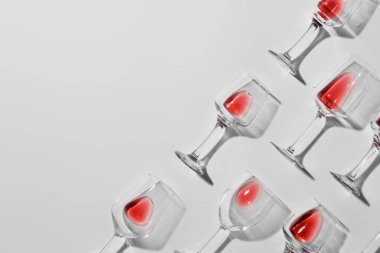 Açık arkaplanda kırmızı şarap artığı olan bardakların şık kompozisyonu