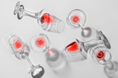 Açık arkaplanda kırmızı şarap artığı olan bardakların şık kompozisyonu