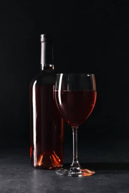 Siyah arka planda bir şişe kırmızı şarap.