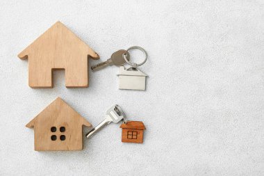 Işık arka planında anahtarlıkları olan ev ve anahtar figürleri