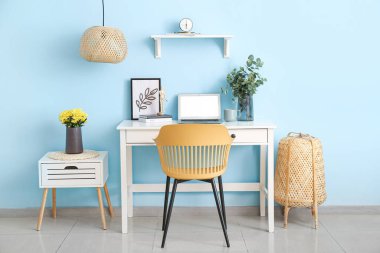 Renk duvarına yakın cam vazosu olan modern bir işyeri.