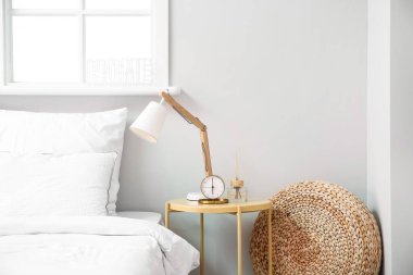 Alarm saati ve şık lamba komodinin üzerinde.