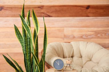 Rahat koltuğun ve ahşap duvarın yanında alarmlı bir masa.