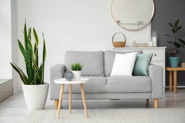 Rahat bir kanepe ve ışık duvarının yanında çalar saati olan bir masa.