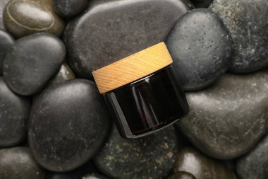 Spa taşları arka planında bir kavanoz kozmetik ürünü