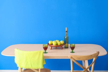 Elmalı yemek masası ve şarap şişesi duvarın yanında.