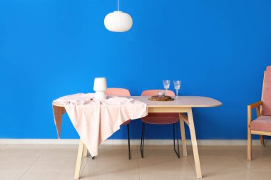 Lambalı yemek masası ve renkli duvarların yanında gözlük.