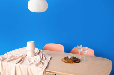 Renk duvarının yanında lamba ve dekor olan yemek masası