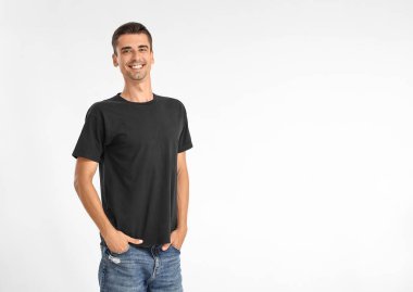 Hafif arka planda şık tişörtlü yakışıklı genç adam.