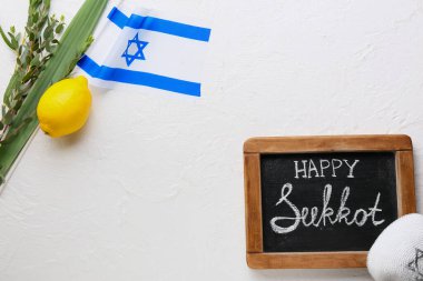 Metni Mutlu SUKKKOT olan tebeşir tahtası, İsrail bayrağı ve arka planda festival sembolleri